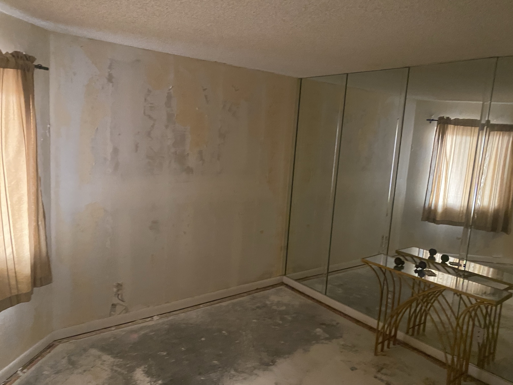 Condo bedroom with damaged walls and stripped finishes before repair